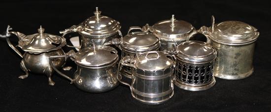 A pair of pierced silver drum mustards and six other silver mustards, all with blue glass liners
